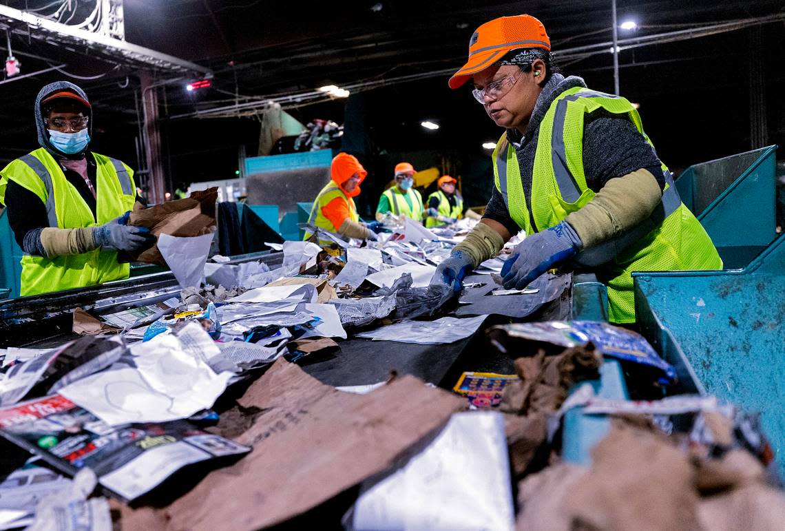 Martina Garcia, right, works on the paper quality control line at a Sonoco materials recovery facility on Tuesday, Jan. 17, 2023, in Raleigh, N.C. The recycling plant receives material from all of Raleigh’s residential blue bins, along with recycling from Durham, Fuquay-Varina and some smaller community drop-off centers.