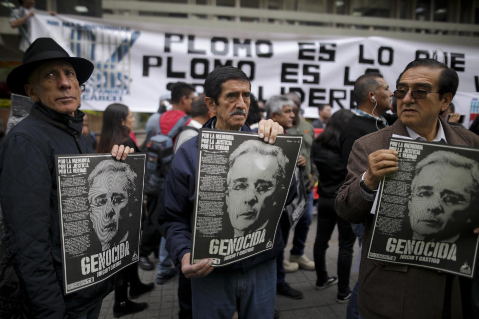 Opponents to former president Alvaro Uribe hold posters, protesting against him, in front of the Supreme Court during Uribe’s hearing in an investigation for witness tampering, in Bogota, Colombia, Tuesday, Oct. 8, 2019. Uribe is being investigated for allegedly trying to influence and possibly bribe members of a former paramilitary group. (AP Photo/Ivan Valencia)