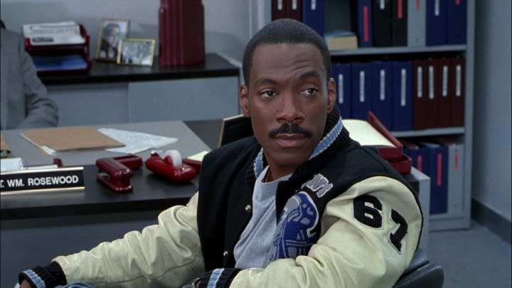 Eddie Murphy sitting with his iconic jacket in an office on Beverly Hills Cop.
