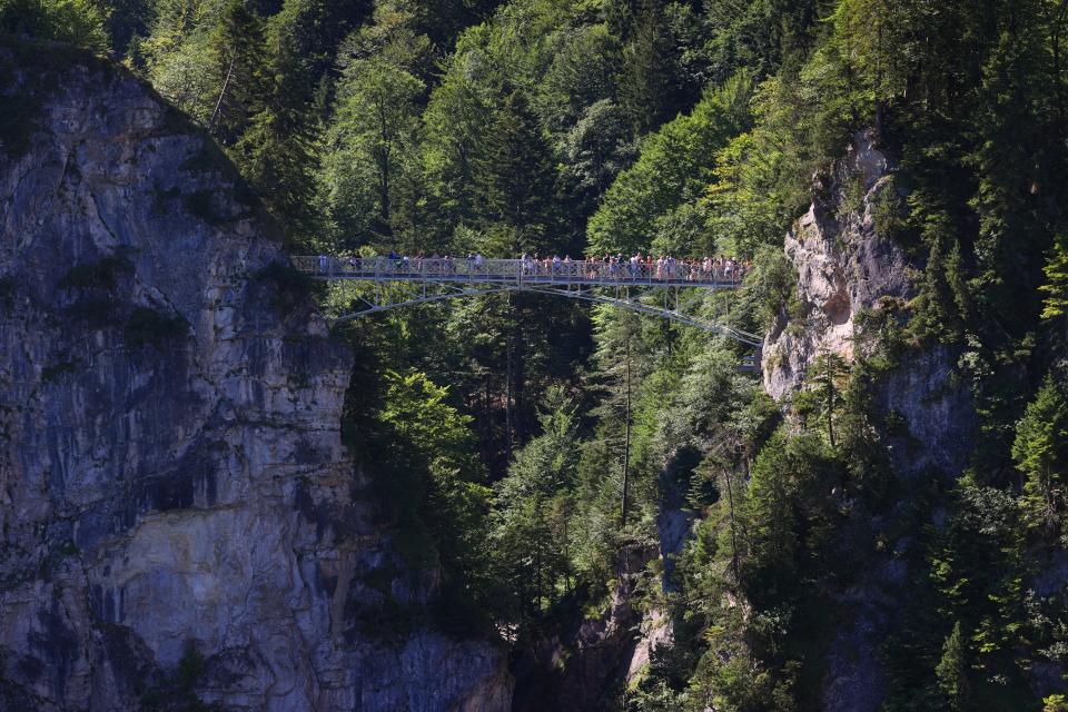 Tourists stand on the Marienbr'cke bridge, near the Neuschwanstein castle, in Schwangau, Germany, Thursday, June 15, 2023. Authorities say an American man has been arrested in Germany after allegedly assaulting two tourists he met near Neuschwanstein castle. The attack, which occurred on Wednesday, left one of the women dead. Police said Thursday that the 30-year-old man met the two women on a hiking path and lured them onto a trail. They said the man then “physically attacked” the younger woman. (Frank Rumpenhorst/dpa via AP) ORG XMIT: SCH804