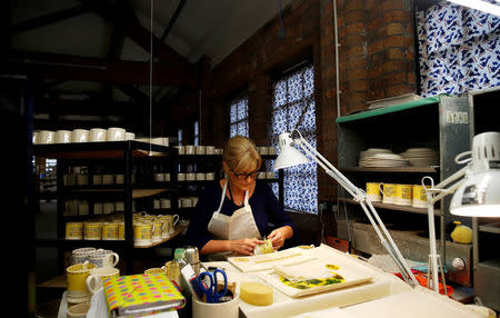 A worker adds transfers to mugs commemorating the wedding of Britain's Prince Harry and Meghan Markle at the Emma Bridgewater Factory, in Hanley, Stoke-on-Trent, Britain March 28, 2018. REUTERS/Carl Recine