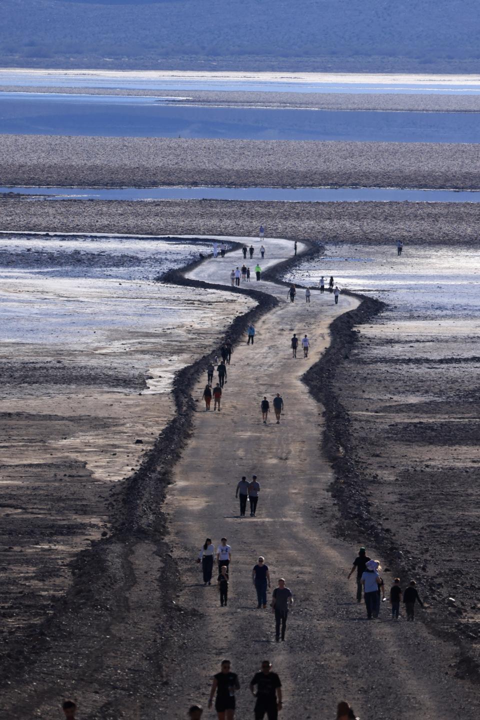 Tourists walk along a path as they enjoy the rare opportunity to see water during their visit to Badwater Basin, the normally driest place in the US, in Death Valley National Park on Sunday.