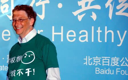 FILE PHOTO: Bill Gates, Microsoft Corp co-founder and co-chair of the Bill and Melinda Gates Foundation, smiles after putting on a shirt bearing the slogan: "Say No to Involuntary Smoking", during a media conference in Beijing June 11, 2011. REUTERS/David Gray/File Photo