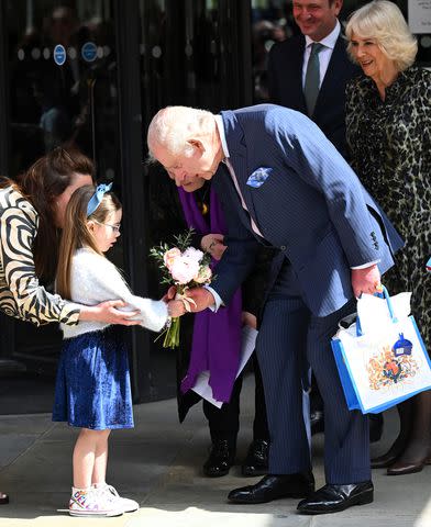 <p>Samir Hussein/WireImage</p> King Chares and Queen Camilla accept a present as they leave the University College Hospital Macmillan Cancer Centre on April 30, 2024 in London.
