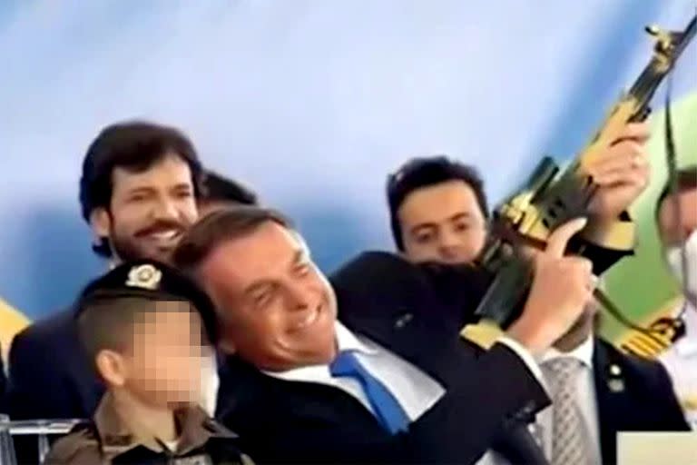 Bolsonaro junto a un niño empuña un arma de juguete en un acto