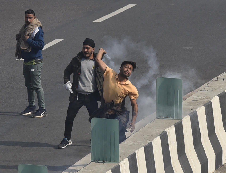 NEW DELHI, INDIA - JANUARY 26: A demonstrator throws back a tear gas cannister fired by poilce at NH-24 near Akshardham during the farmers' tractor rally on Republic Day, on January 26, 2021 in New Delhi, India. Major scenes of chaos and mayhem at Delhi borders as groups of farmers allegedly broke barricades and police check posts and entered the national capital before permitted timings. Police used tear gas at Delhi's Mukarba Chowk to bring the groups under control. Clashes were also reported at ITO, Akshardham. Several rounds of talks between the government and protesting farmers have failed to resolve the impasse over the three farm laws. The kisan bodies, which have been protesting in the national capital for almost two months, demanding the repeal of three contentious farm laws have remained firm on their decision to hold a tractor rally on the occasion of Republic Day.(Photo by Sanjeev Verma/Hindustan Times via Getty Images)