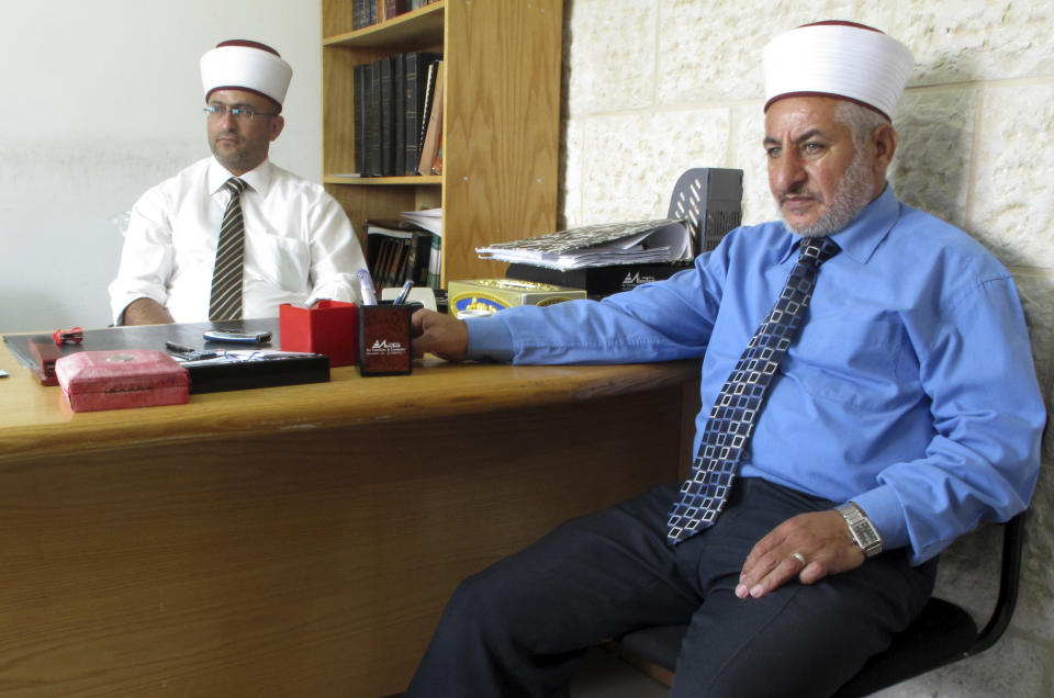 In this photo taken Wednesday, Aug. 29, 2012, two Islamic law judges wearing their traditional hats signifying their position sit in an office in the religious courts in the West Bank city of Ramallah, where Muslim Palestinians register marriages and file for divorce. (AP Photo/Diaa Hadid)