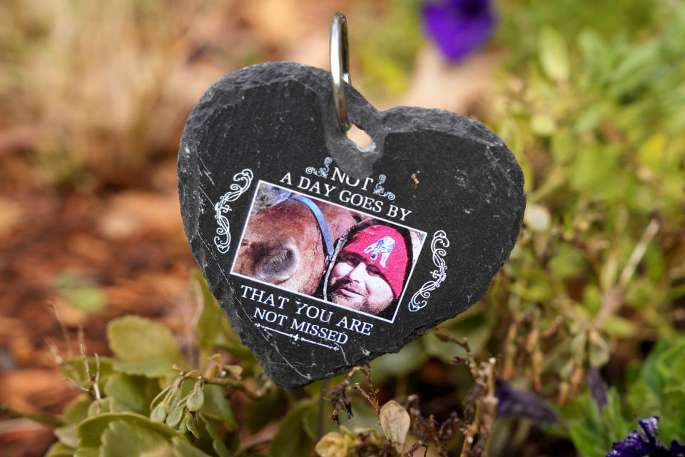 A carved stone heart with a photo of Lynn Wencus's son Jeff, rests in a garden, Tuesday, Nov. 7, 2023, at her home, in Wrentham, Mass. Wencus lost Jeff to a heroin overdose in 2017. The heart was a gift to her from her son-in-law on Mother's Day, May 14, 2023. (AP Photo/Steven Senne)