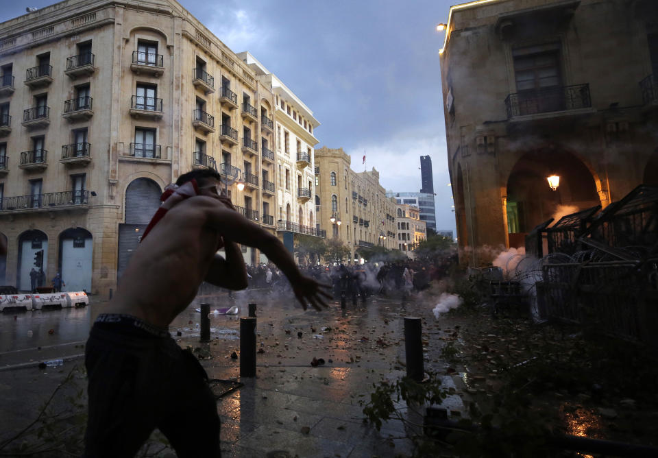 Anti-government demonstrators clash with riot police at a road leading to the parliament building in Beirut, Lebanon, Saturday, Jan. 18, 2020. Riot police fired tears gas and sprayed protesters with water cannons near parliament building to disperse thousands of people after riots broke out during a march against the ruling elite amid a severe economic crisis. (AP Photo/Hassan Ammar)