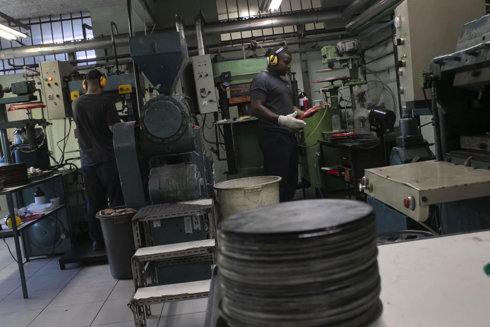 Operators work in the pressing stage of vinyl records production at the Polysom factory in Belford Roxo, Brazil, Tuesday, April 16, 2024. Vinyl’s comeback in Brazil follows a global trend over the last 15 years. In the U.S. alone, revenues from vinyl records hit $1.4 billion in 2023, according to the Recording Industry Association of America. (AP Photo/Bruna Prado)