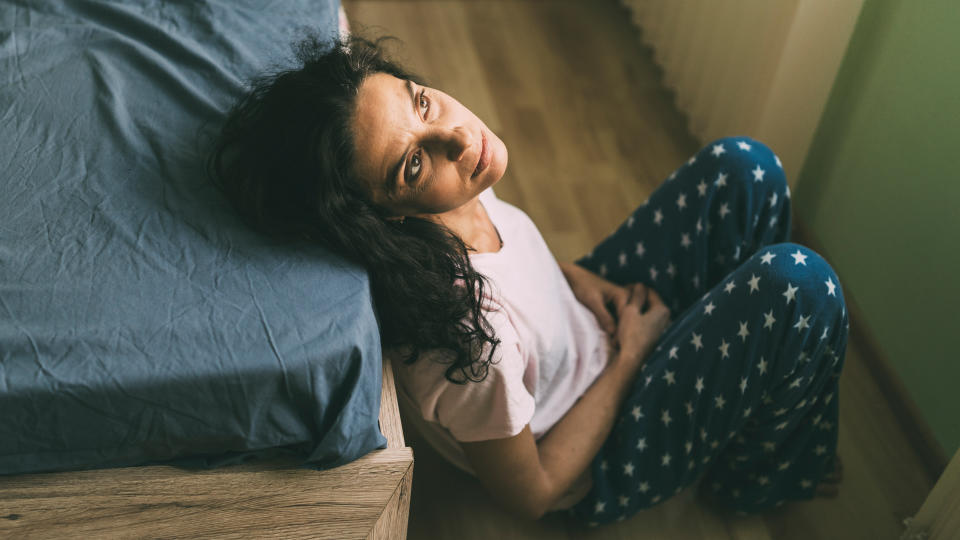 Mid age woman having problems sitting in her bedroom.