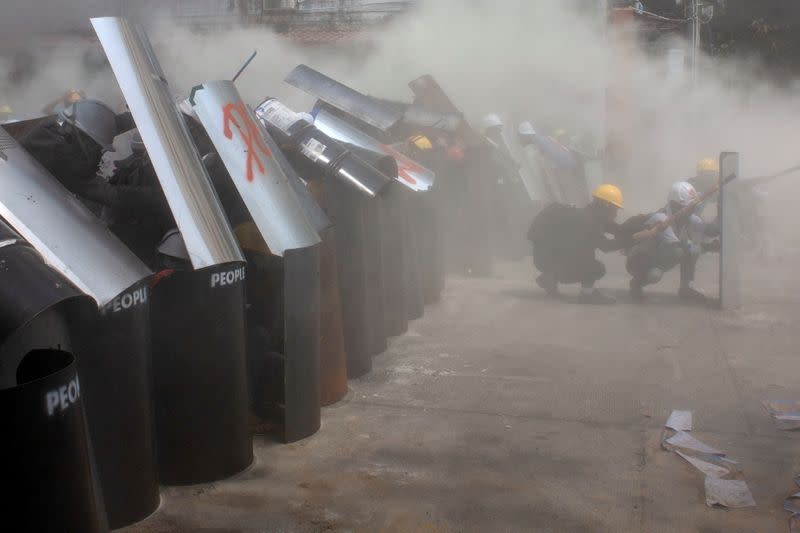 Protesters cover with makeshift shields during an anti-coup protest in Yangon