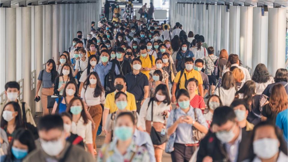 Grupo de personas caminando con mascarilla.