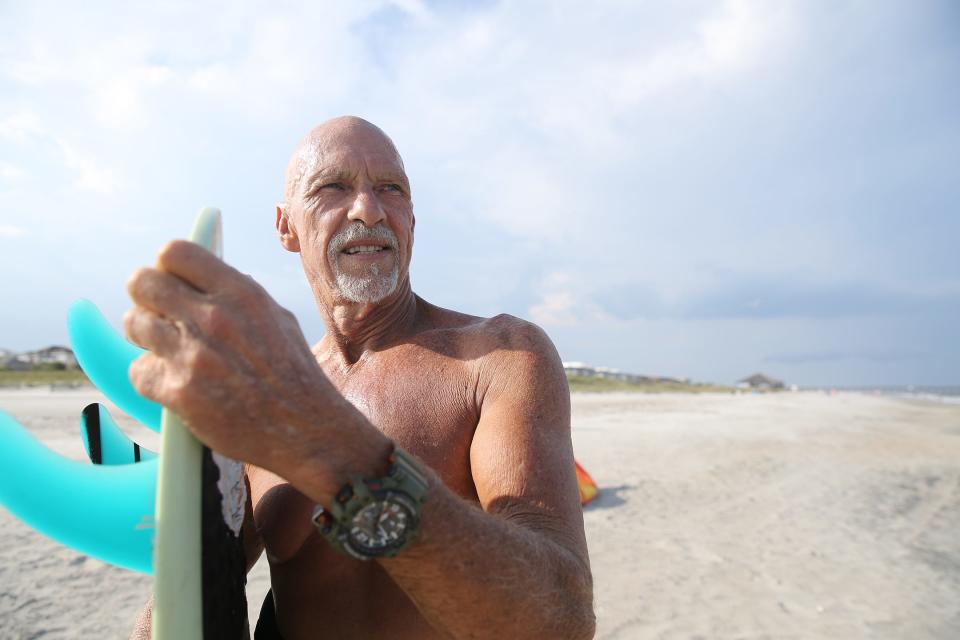 Mack Kitchens stands on the beach at Tybee Island after partaking in one of his favorite activities, kite surfing. Kitchens holds a special surf board given to him by the City of Tybee after his was lost while rescuing a drowning teenager in 2021.