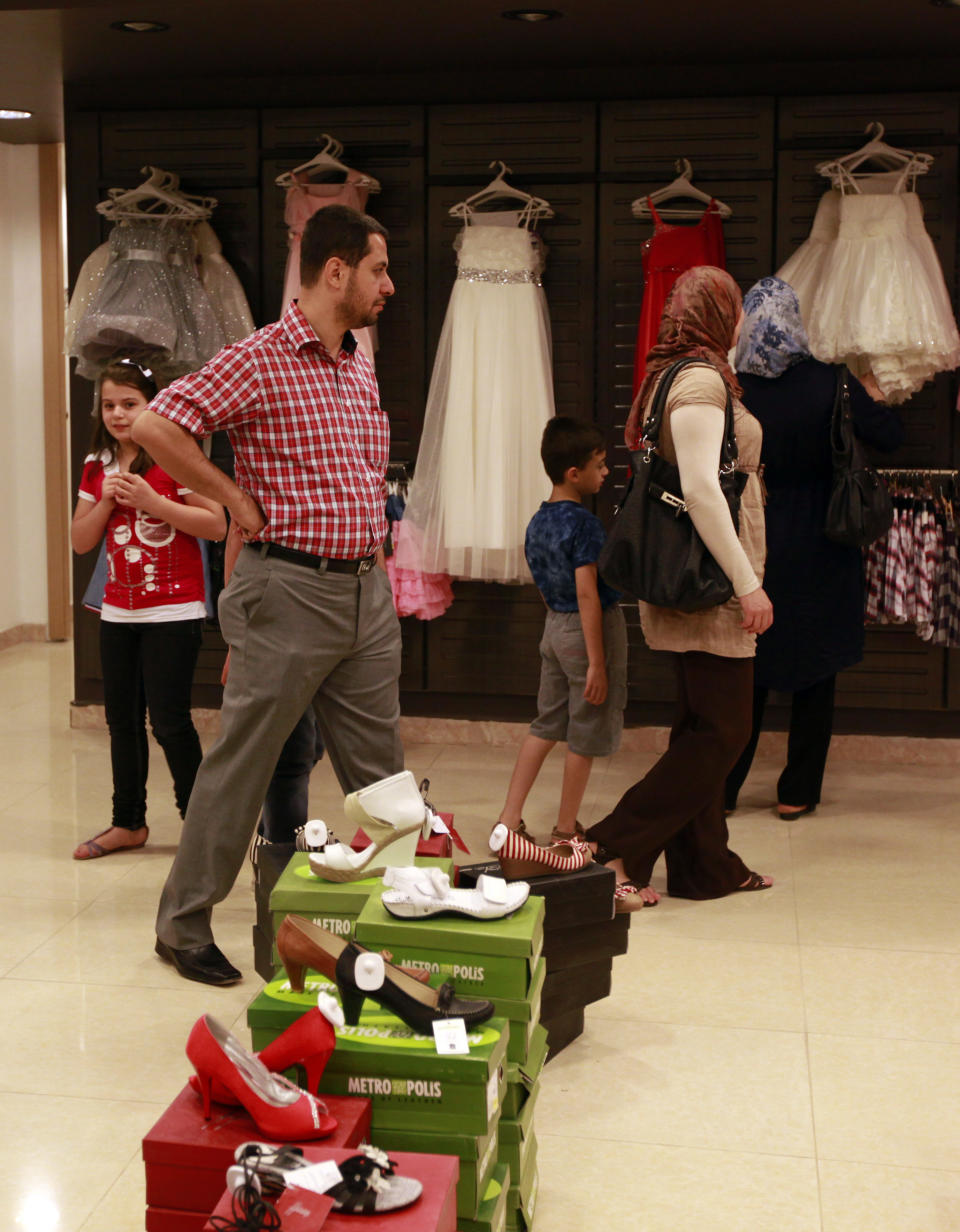 In this photo taken on Saturday, June 2, 2012, people shop at a department store in Baghdad's Azamiya neighborhood, Iraq. For residents of Azamiya, once one of Baghdad's most violent neighborhoods, the opening of a department store selling party dresses, imported men's suits and designer label perfumes is a hopeful sign that the worst may finally be behind them. (AP Photo/Hadi Mizban)