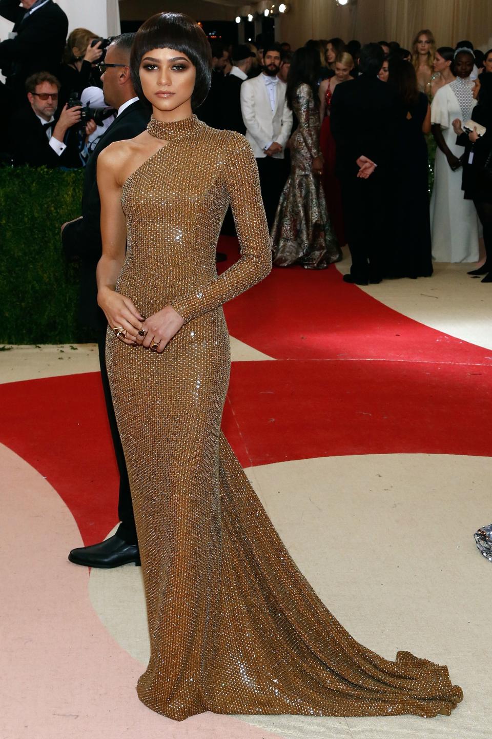 Zendaya in a long-sleeve, mesh, body-hugging gown with a high neck and trail at a gala