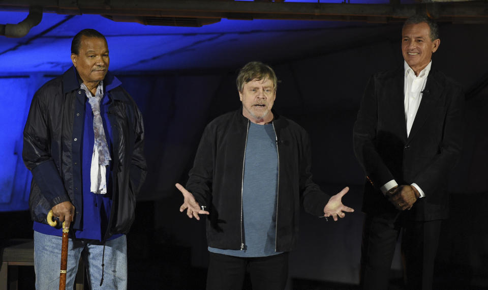 "Star Wars" film franchise cast member Mark Hamill, center, addresses the crowd as fellow cast member Billy Dee Williams, left, and Walt Disney Co. Chairman and CEO Bob Iger look on during a dedication ceremony for the new Star Wars: Galaxy's Edge attraction at Disneyland Park, Wednesday, May 29, 2019, in Anaheim, Calif. (Photo by Chris Pizzello/Invision/AP)