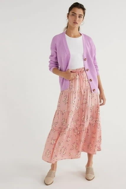 model in lilac cardigan, white top, and floral pink skirt