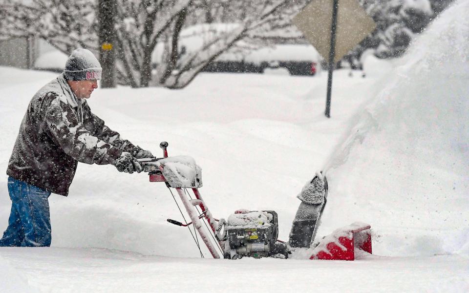 Darrell Chesley clears the snow from his driveway in Wellsville, Utah, as winter weather caused the cancellation of more than 1,800 flights across the US - Eli Lucero/The Herald Journal via AP