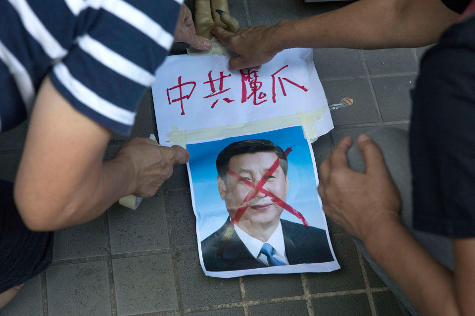 <p>Pro-democracy activists paste the words “Chinese Communist Demon Claws” on a defaced photo of Chinese President Xi Jinping before attempting to march in protest towards the venue where official ceremonies are held to mark the 20th anniversary of Chinese rule over Hong Kong in Hong Kong, Saturday, July 1, 2017. (Photo: Ng Han Guan/AP) </p>