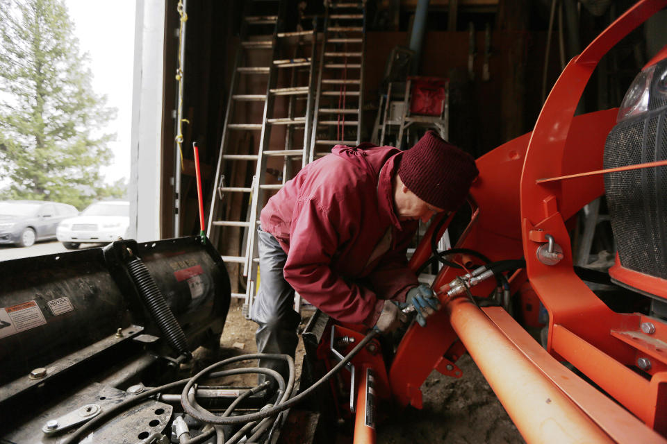 Thubten Losang, a fully ordained Buddhist monk, connects a hydraulic line from a snow plow attachment to a tractor at Sravasti Abbey, Thursday, Nov. 18, 2021, in Newport, Wash. (AP Photo/Young Kwak)