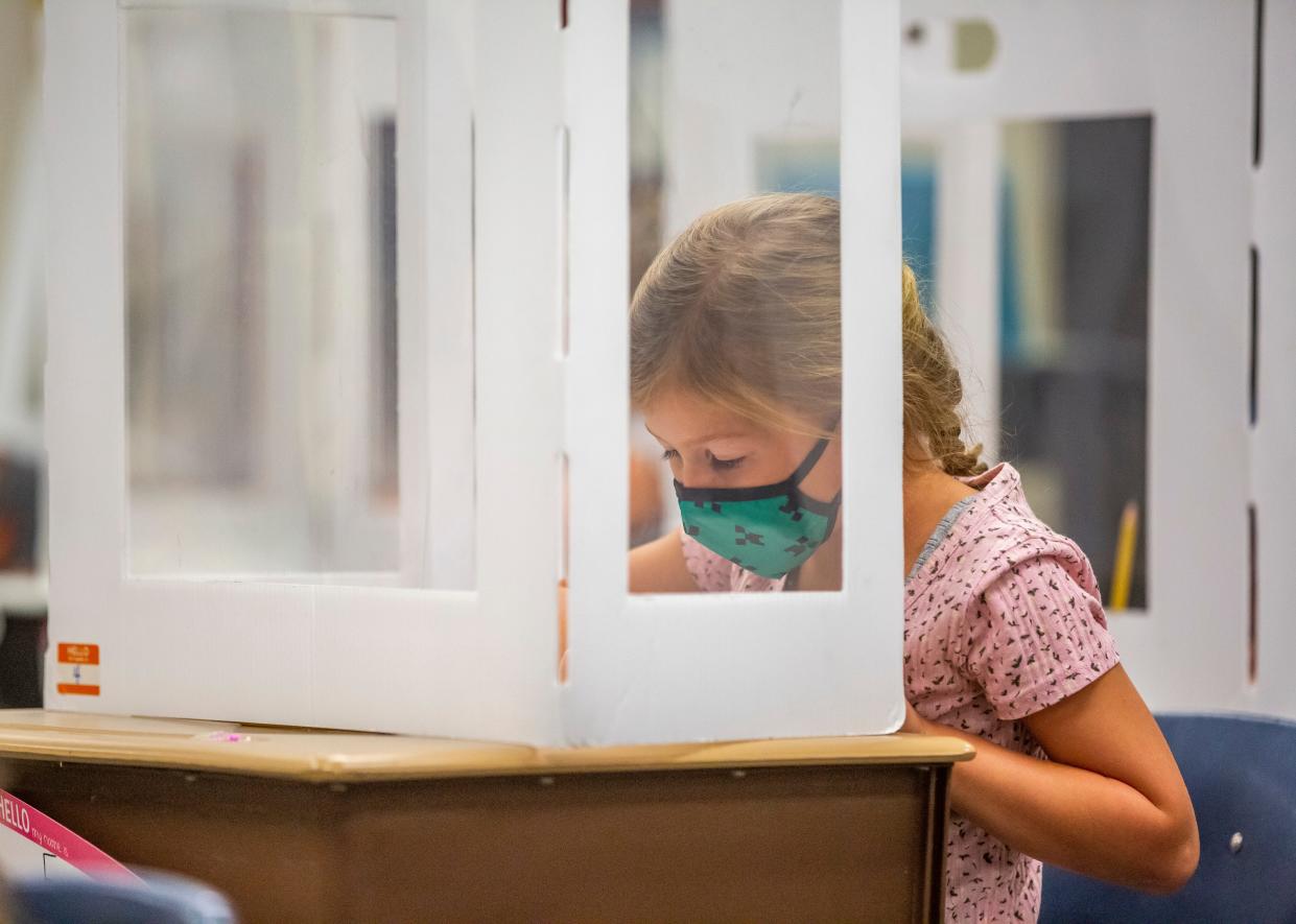 Hums Elementary School first grader Emma Foster works at her desk while sitting at a desk with a cardboard divider on Thursday, Sept. 2, 2021, in Mishawaka. 