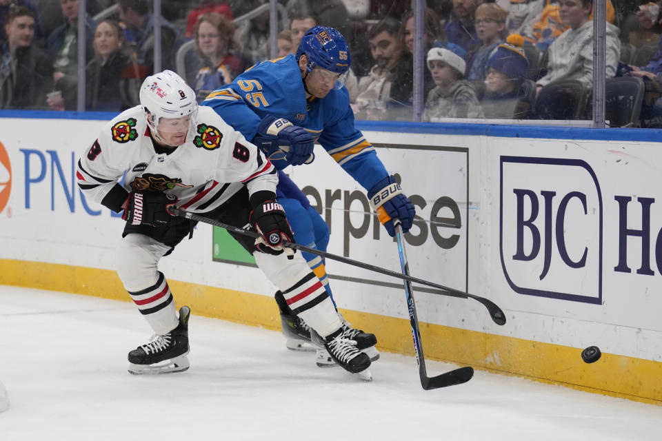 St. Louis Blues' Colton Parayko (55) and Chicago Blackhawks' Ryan Donato (8) chase after a loose puck during the first period of an NHL hockey game Saturday, Dec. 23, 2023, in St. Louis. (AP Photo/Jeff Roberson)