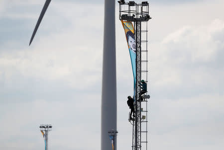 Greenpeace activists unfurl a banner from a lighting tower after activists entered the vehicle park in a protest against Volkswagen diesel vehicles at the port of Sheerness, Britain, September 21, 2017. REUTERS/Peter Nicholls