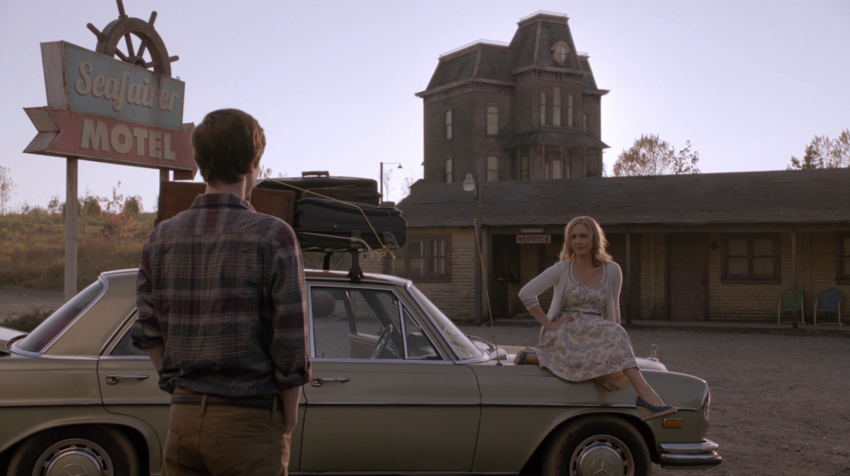 Freddy Highmore looks at Vera Farmiga sitting on a car in front of the Bates Motel