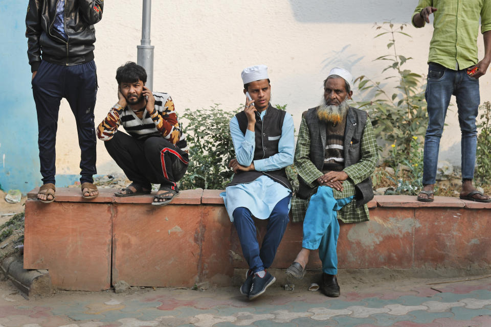 People wait to collect bodies of relatives who died in a fire in New Delhi, India, Sunday, Dec. 8, 2019. Dozens of people died on Sunday in a devastating fire at a building in a crowded grains market area in central New Delhi, police said. (AP Photo/Manish Swarup)