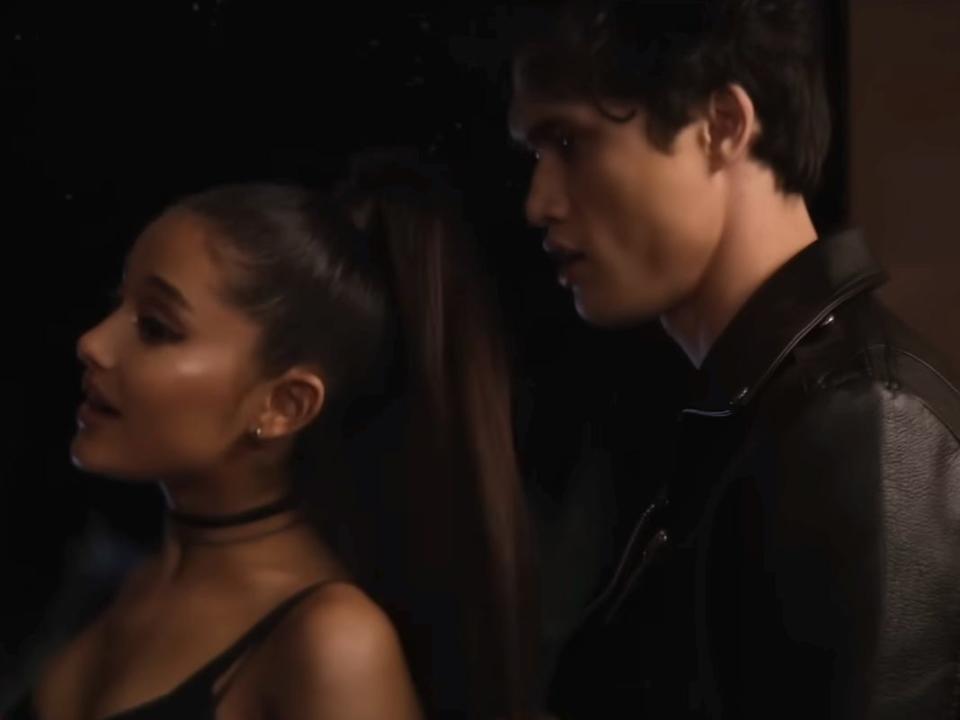 charles melton looking at ariana grande and another woman interact in front of him