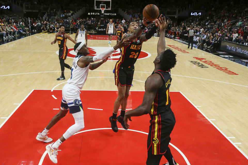 Atlanta Hawks forward John Collins (20) grabs a rebound past Minnesota Timberwolves forward Jaden McDaniels, left, as Clint Capela reaches for the ball in the first half of an NBA basketball game, Monday, March 13, 2023, in Atlanta. (AP Photo/Brett Davis)