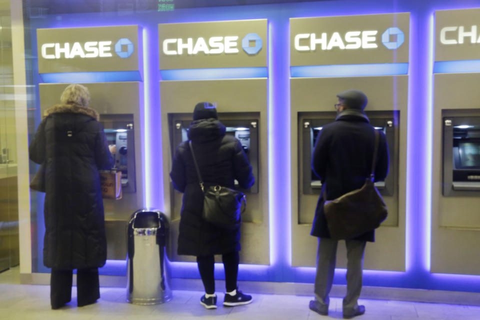 Customers uses ATM's at at a branch of Chase Bank, Wednesday, Jan. 14, 2015 in New York.  JPMorgan Chase reported a 7 percent drop in fourth-quarter earnings Wednesday, hit by more legal costs and a drop in trading revenue. JPMorgan, the biggest U.S. bank by assets, said it earned $4.93 billion, or $1.19 a share, for the three-month period ending in December. (AP Photo/Mark Lennihan)
