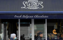 A woman in a protective mask walks by a Belgian chocolate shop in the center of Antwerp, Belgium, Saturday, March 14, 2020. Belgium has closed schools, restaurants and bars, as as well as cancelled sporting and cultural events in an effort to contain the spread of the coronavirus. For most people, the new coronavirus causes only mild or moderate symptoms, such as fever and cough. For some, especially older adults and people with existing health problems, it can cause more severe illness, including pneumonia. (AP Photo/Virginia Mayo)