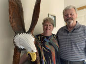 In this Friday, June 28, 2019, photo, Vicki and Larry Eklund pose with their 7-foot-tall bald eagle carving at their home in Coon Rapids, Minn. When the Eklund's 150-pound bald eagle carving was stolen from their yard earlier this year, police in the Minneapolis suburb of Coon Rapids had a key piece of evidence: an image of the suspect looking directly into Eklund's doorbell camera. Police posted the Ring doorbell video on social media, and hours later the Army veteran's valued carving was returned. (AP Photo/Jeff Baenen)