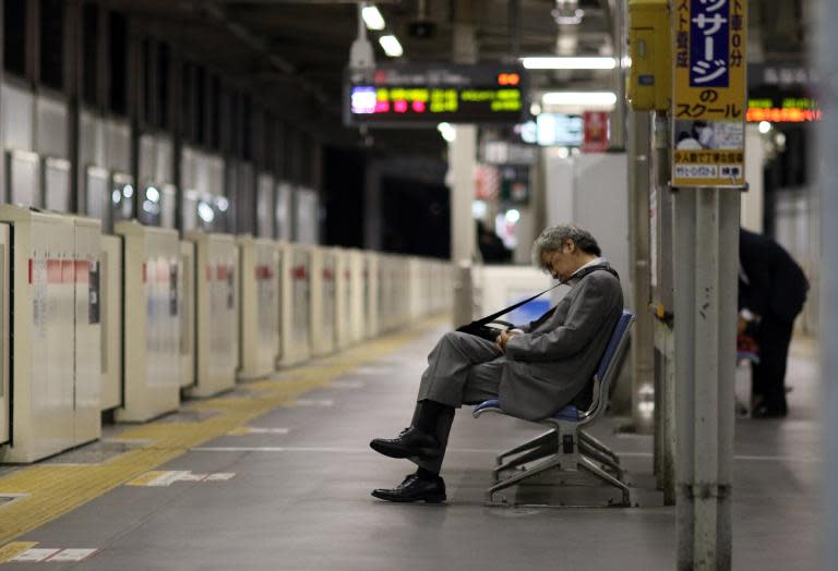 A businessman is seen napping on a bench at a Tokyo train station