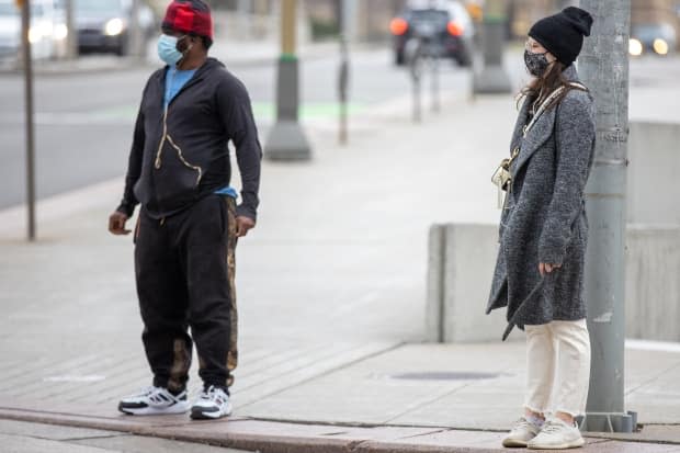 Masked pedestrians wait at an intersection in downtown Ottawa in May 2021.