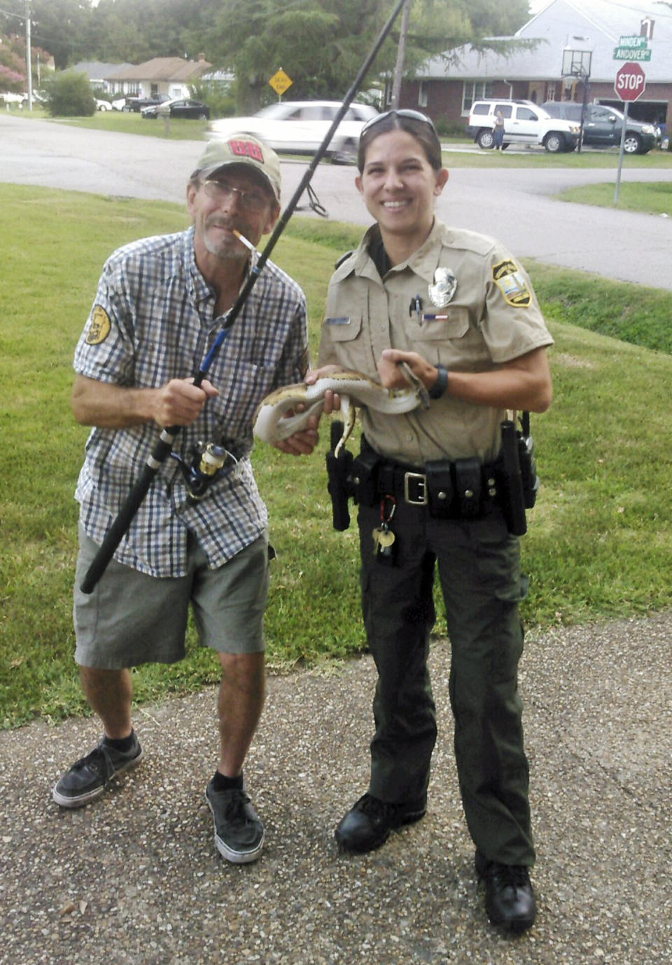 Kenny Spruill and and unidentified officer pose with a snake after he removed it from the toilet. Source: AAP