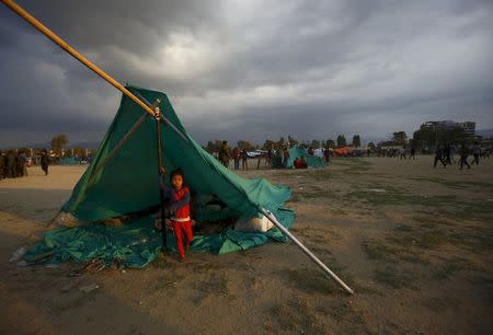 A child stands inside a makeshift shelter in an open ground to keep safe after an earthquake in Kathmandu, Nepal April 26, 2015. REUTERS/Navesh Chitraka