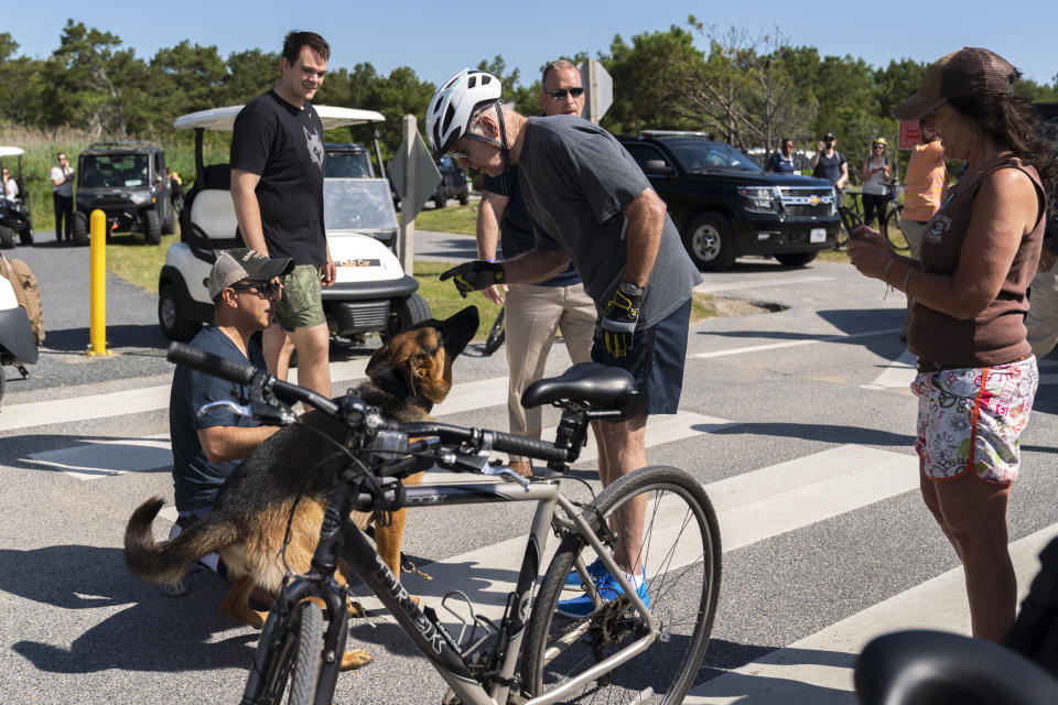 President Joe Biden communicates to his dog Commander after greeting a crowd at Gordons Pond in Rehoboth Beach, Del., Saturday, June 18, 2022. Biden fell as he tried get off his bike to greet the crowd along the trail. (AP Photo/Manuel Balce Ceneta)