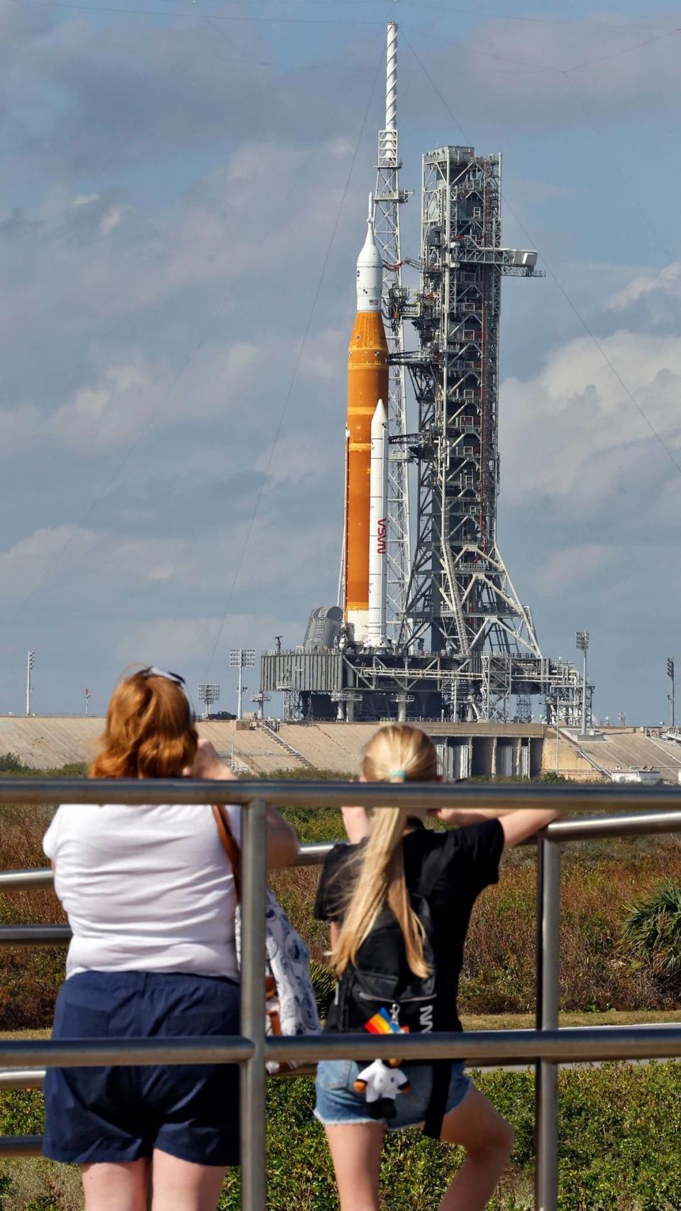 Los visitantes del Centro Espacial Kennedy ven el nuevo cohete lunar de la NASA en la plataforma de lanzamiento 39-B, el lunes 14 de noviembre de 2022 en Cabo Cañaveral, Florida. El programa de exploración lunar del siglo XXI de la NASA, llamado Artemis en honor a la hermana gemela mitológica de Apolo. La NASA tiene como objetivo un intento de lanzamiento el miércoles por la mañana temprano. (Foto AP/Terry Renna)