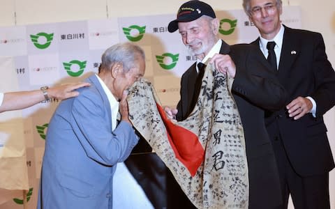 WWII veteran Marvin Strombo, center, returns Tatsuya Yasue, left, a Japanese flag with autographed messages which was owned by his brother Sadao Yasue, who was killed in the Pacific during World Work II, during a ceremony in Higashishirakawa - Credit: Eugene Hoshiko /ap