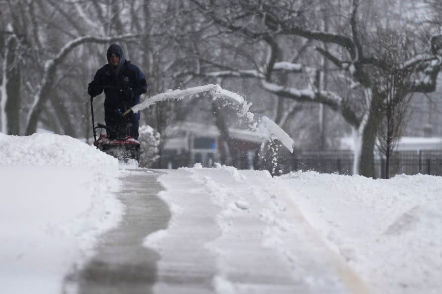 A man cleans the snow off a walkway in front of a house in Wheeling, Ill., Friday, Jan. 12, 2024. (AP Photo/Nam Y. Huh)