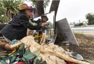 Dawn Woodward, 39, who is homeless and originally from Arizona, dusts a mirror set outdoors in a homeless camp on the side of the CA-101 highway in the Echo Park neighborhood in Los Angeles Tuesday, May 11, 2021. California Gov. Gavin Newsom on Tuesday proposed $12 billion in new funding to get more people experiencing homelessness in the state into housing and to “functionally end family homelessness” within five years. (AP Photo/Damian Dovarganes)