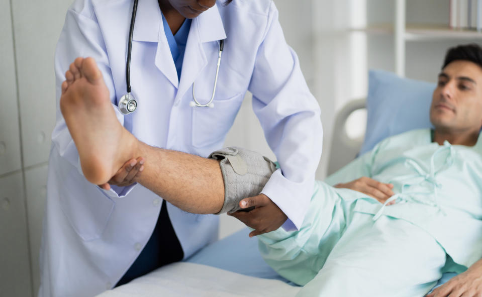 Healthcare professional examining patient's leg in a hospital room
