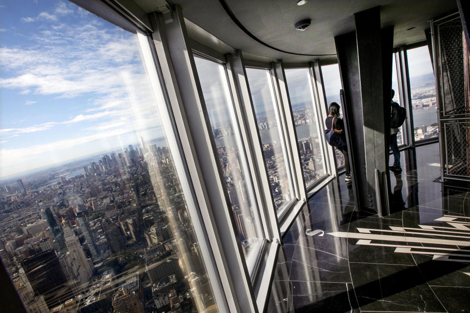 People look at the view from the 102nd floor observatory of the Empire State Building, in New York, Thursday, Oct. 10, 2019. The world-famous observatory atop the Empire State Building has a dizzying new look with floor-to-ceiling, 360-degree windows 102 floors above New York City.(AP Photo/Richard Drew)