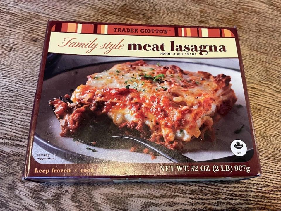 Package of Trader Joe's family-style meat lasagna with a photo of lasagna on the box placed on a wooden counter