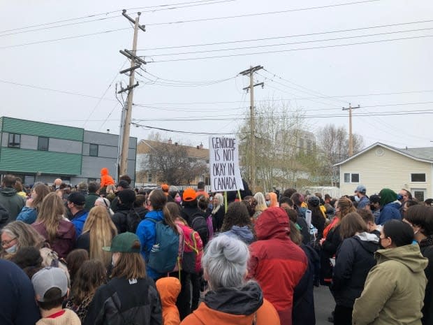 A sign at the Dene Nation memorial gathering on Friday reads, 'genocide is not okay in Canada.'