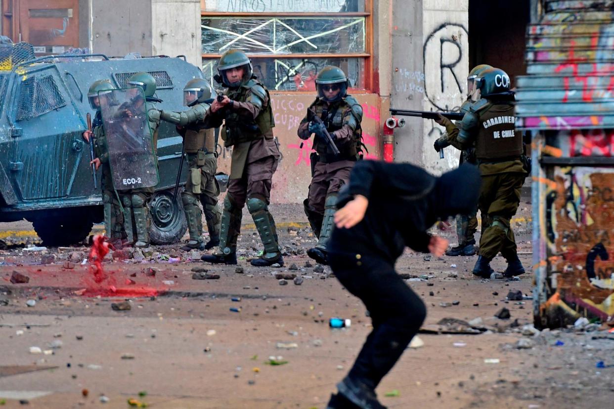 Riot police aim at a demonstrator during a protest in Chile: AFP via Getty Images