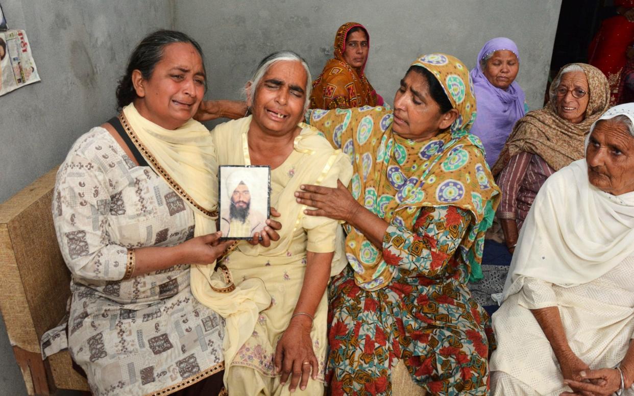 Relatives mourn holding a portrait of Gurcharan Singh, one of the 38 Indian workers whose bodies were found buried northwest of Mosul - AP